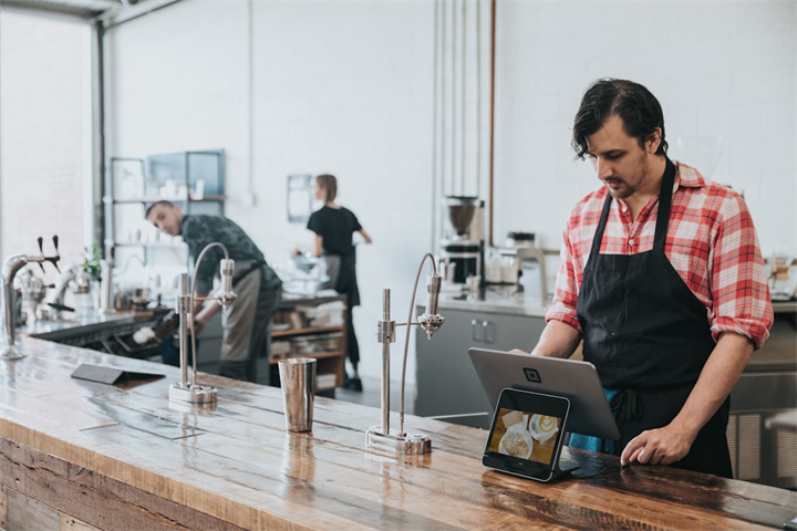 Cafe staff using POS and laptop during service